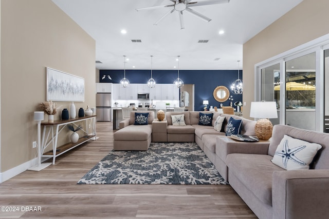 living room featuring light wood-type flooring and ceiling fan with notable chandelier