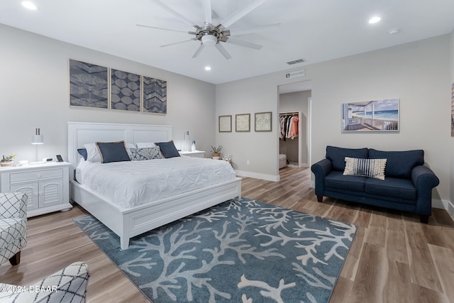 bedroom featuring a walk in closet, ceiling fan, a closet, and hardwood / wood-style flooring