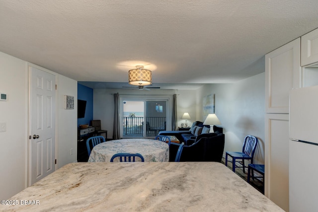 bedroom with white refrigerator, access to exterior, and a textured ceiling