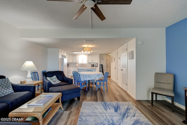 living room with ceiling fan, hardwood / wood-style floors, and a textured ceiling