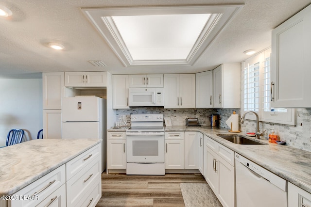 kitchen with sink, white cabinetry, a textured ceiling, light wood-type flooring, and white appliances