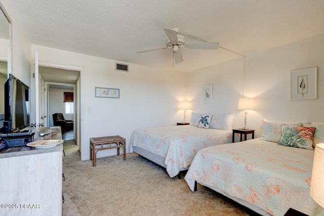 bedroom featuring ceiling fan, light colored carpet, and a textured ceiling