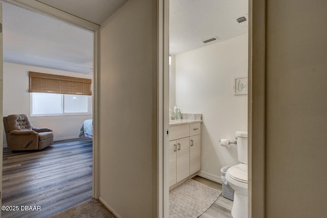 bathroom featuring vanity, hardwood / wood-style flooring, and toilet