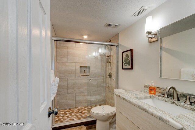 bathroom with walk in shower, vanity, a textured ceiling, and toilet