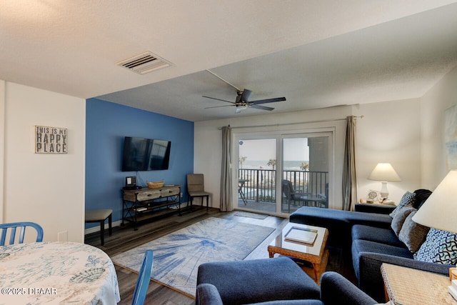 living room with hardwood / wood-style flooring, ceiling fan, and a textured ceiling