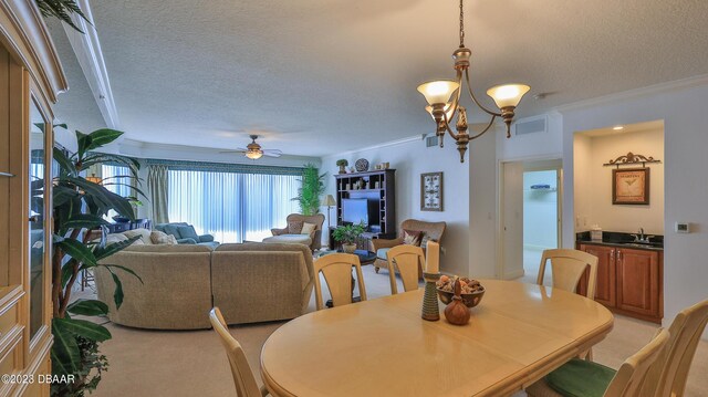 carpeted dining space featuring a textured ceiling, ceiling fan with notable chandelier, ornamental molding, and sink