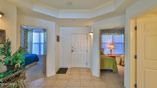 carpeted entryway featuring ornamental molding and a tray ceiling