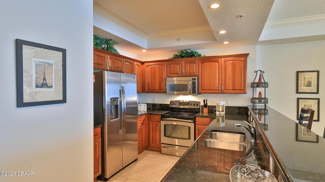 kitchen featuring sink, ornamental molding, a textured ceiling, appliances with stainless steel finishes, and a tray ceiling