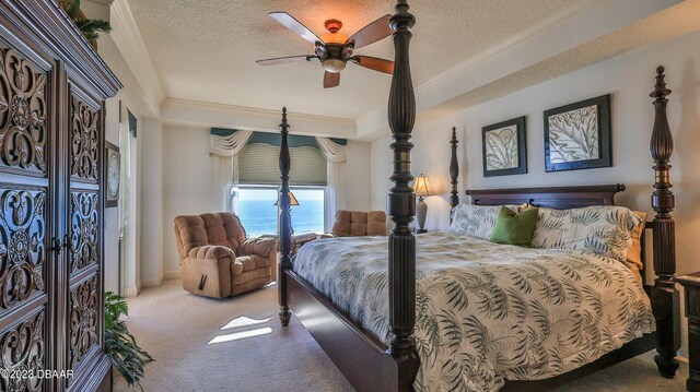 bedroom with a textured ceiling, a water view, ceiling fan, and light colored carpet