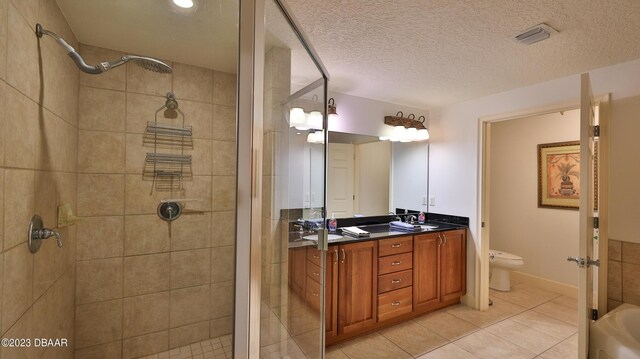 bathroom featuring vanity, a shower with door, tile patterned floors, toilet, and a textured ceiling