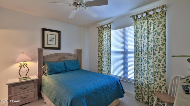 bedroom with multiple windows, ceiling fan, and light carpet