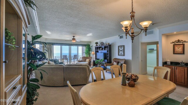 dining space featuring carpet, a textured ceiling, ceiling fan with notable chandelier, crown molding, and sink