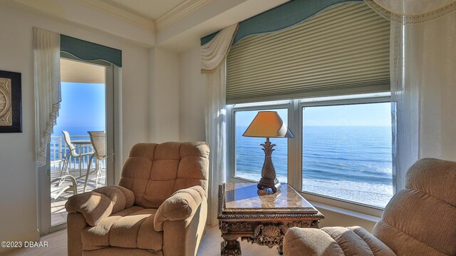 living area with carpet flooring, a water view, and crown molding