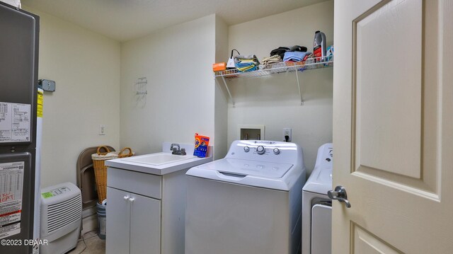 clothes washing area featuring cabinets, washing machine and dryer, light tile patterned floors, and sink