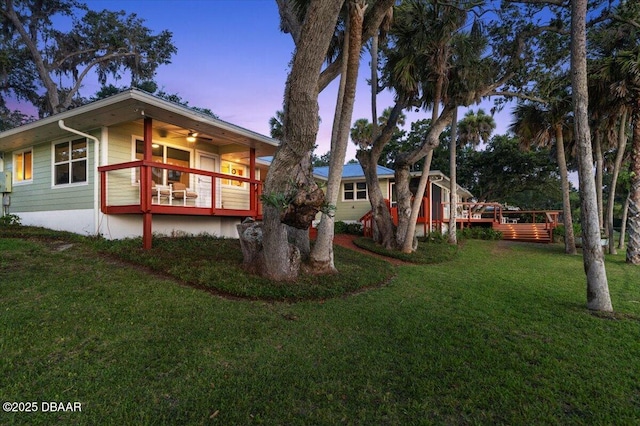 101 Azalea Cir, New Smyrna Beach, FL 32168 - back of house at dusk with a lawn and a wooden deck