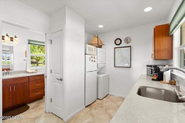 101 Azalea Cir, New Smyrna Beach, FL 32168 - kitchen with white appliances, stacked washing machine and dryer, light countertops, brown cabinets, and recessed lighting