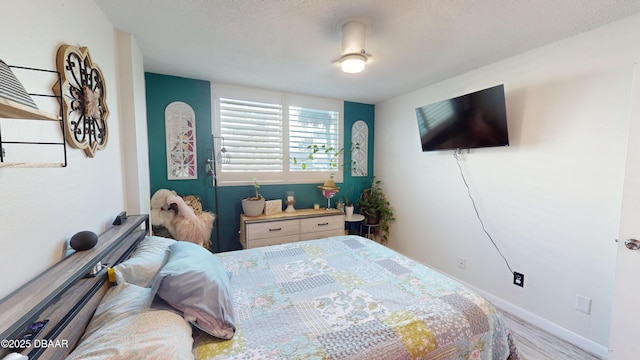 bedroom featuring a textured ceiling, baseboards, and wood finished floors