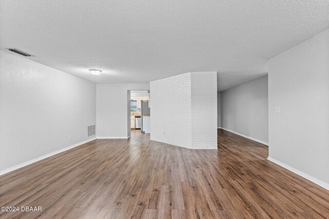 unfurnished living room featuring wood-type flooring and a textured ceiling