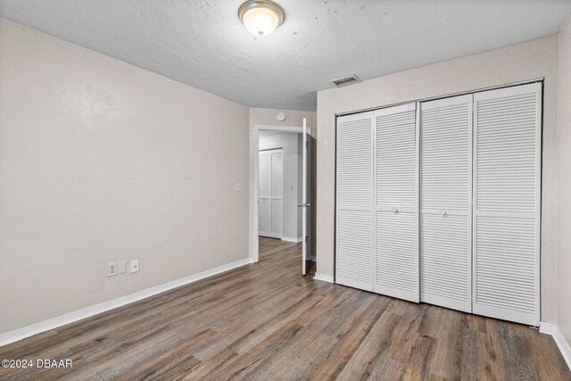 unfurnished bedroom featuring dark hardwood / wood-style flooring and a closet