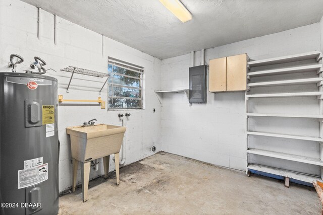 basement featuring electric panel, electric water heater, and sink