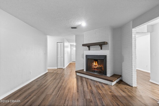 unfurnished living room with a textured ceiling, a fireplace, and dark hardwood / wood-style floors