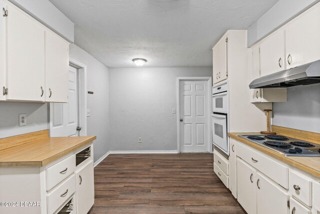 kitchen featuring stainless steel electric stovetop, white cabinetry, double oven, and dark wood-type flooring