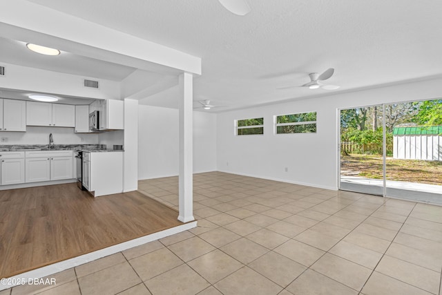 kitchen featuring visible vents, stainless steel microwave, ceiling fan, plenty of natural light, and a sink