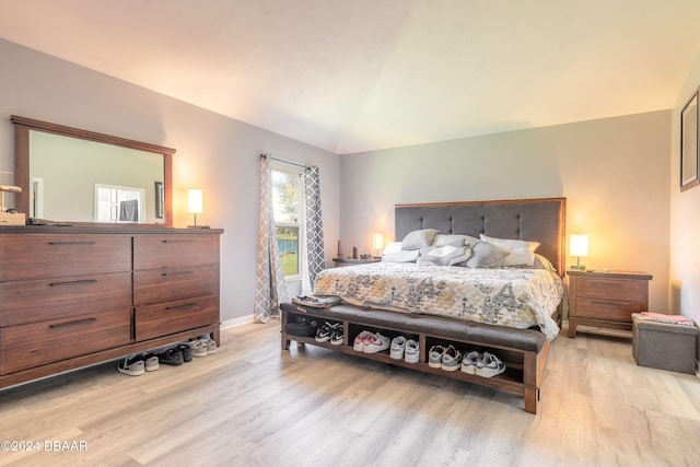 bedroom featuring light wood-type flooring, baseboards, and lofted ceiling