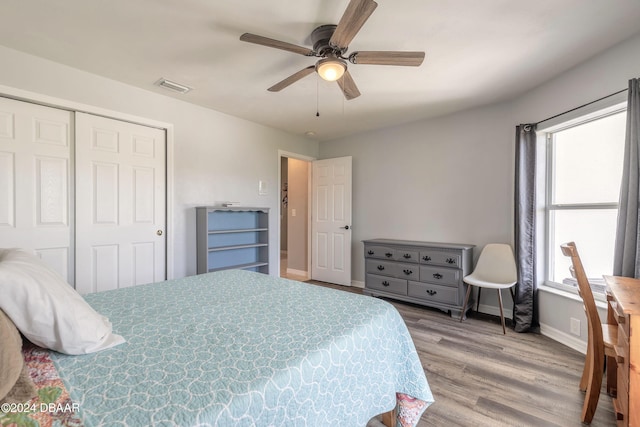 bedroom with multiple windows, a closet, hardwood / wood-style floors, and ceiling fan