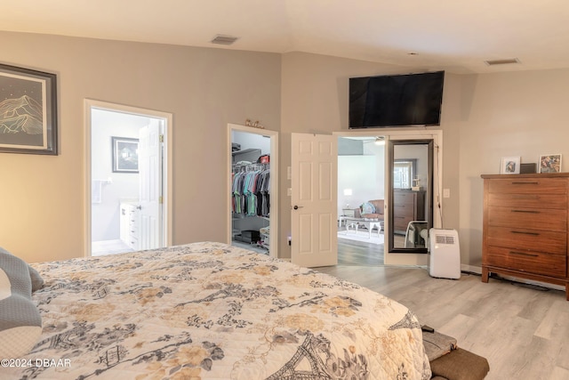 bedroom with ensuite bath, light wood-type flooring, a walk in closet, and a closet