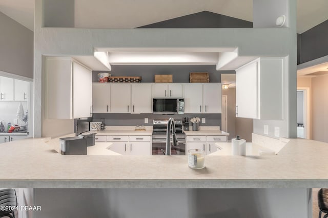 kitchen with kitchen peninsula, appliances with stainless steel finishes, and white cabinetry