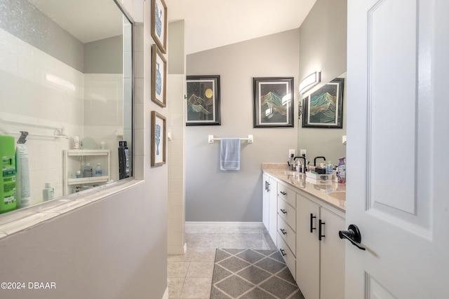 bathroom featuring tile patterned floors, vanity, a shower, and vaulted ceiling