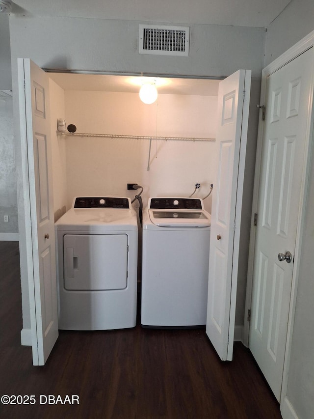 washroom with washing machine and clothes dryer, visible vents, laundry area, and dark wood-style flooring
