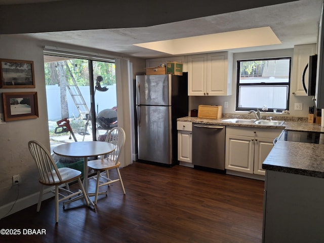 kitchen with stainless steel appliances, dark wood-style flooring, a sink, and white cabinetry