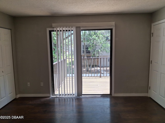 interior space featuring dark wood-type flooring, a textured ceiling, and baseboards