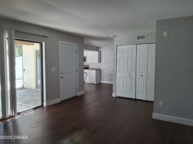 unfurnished living room featuring visible vents, baseboards, and dark wood-style flooring