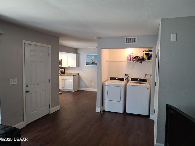 laundry area with laundry area, baseboards, visible vents, dark wood-type flooring, and washer and dryer