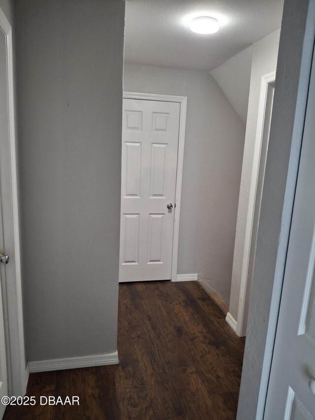 hall featuring vaulted ceiling, baseboards, and wood finished floors