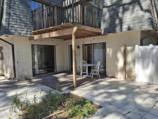 exterior space with mansard roof, a shingled roof, and stucco siding