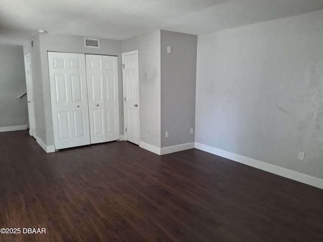 unfurnished bedroom with baseboards, dark wood-type flooring, and visible vents
