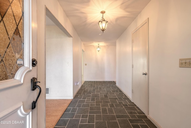 hallway featuring baseboards and visible vents