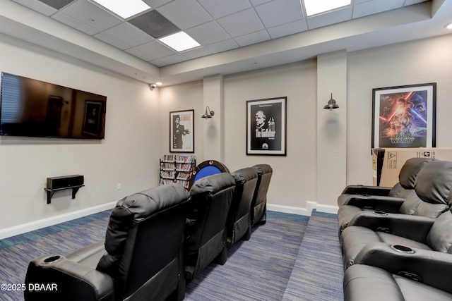 home theater room featuring a paneled ceiling, dark carpet, and baseboards