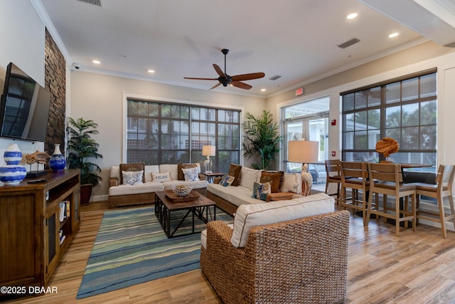 living room featuring crown molding, visible vents, and light wood-style floors