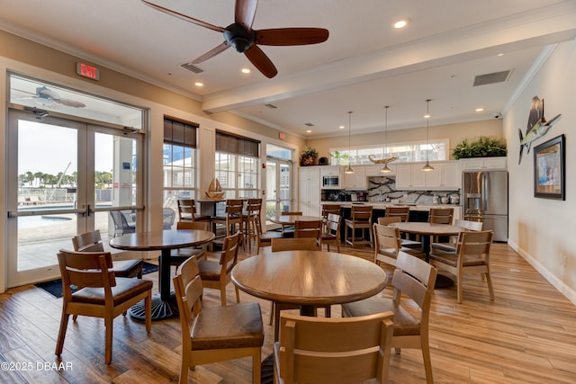 dining room featuring french doors, light wood-type flooring, visible vents, and crown molding