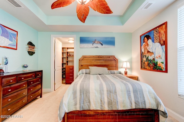 carpeted bedroom featuring a raised ceiling, visible vents, and baseboards