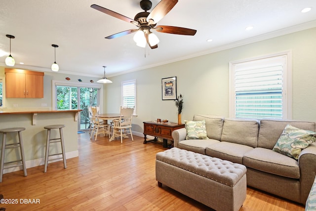 living room with crown molding, ceiling fan, and light wood-type flooring