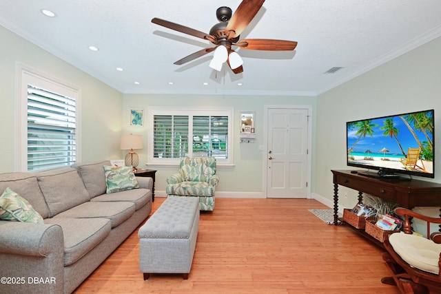 living room with a healthy amount of sunlight, ornamental molding, and light hardwood / wood-style flooring