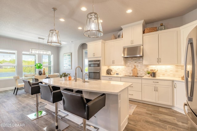 557 Mosaic Blvd, Daytona Beach, FL 32124 - kitchen with under cabinet range hood, recessed lighting, stainless steel appliances, decorative backsplash, and light stone countertops