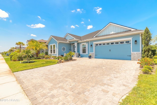 557 Mosaic Blvd, Daytona Beach, FL 32124 - ranch-style home featuring board and batten siding, decorative driveway, an attached garage, stone siding, and a front lawn