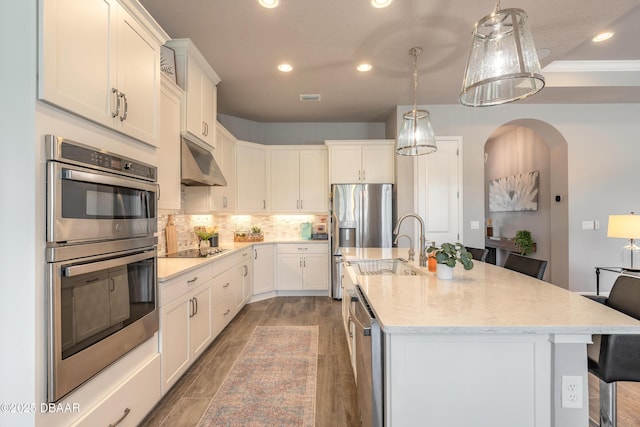 557 Mosaic Blvd, Daytona Beach, FL 32124 - kitchen featuring appliances with stainless steel finishes, under cabinet range hood, a kitchen breakfast bar, light stone countertops, and tasteful backsplash
